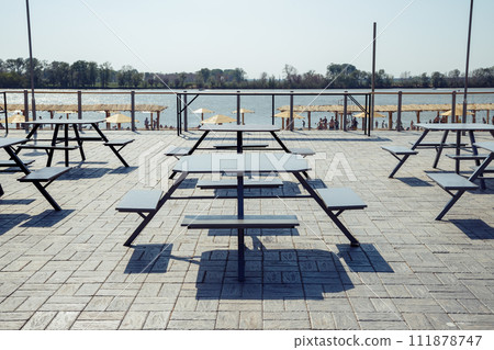 Outdoor furniture benches with table on outside open terrace beach cafe, fast food takeaway. Summer terrace with tables for picnic. No people. 111878747