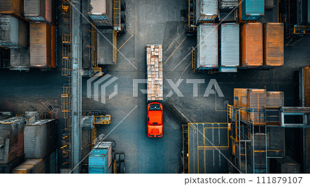From a bird's-eye perspective, an industrial freight truck is seen being loaded with goods amidst a complex of containers and pallets at a busy distribution center, organized for efficiency. From a bird's-eye perspective, an industrial freight truck is seen being loaded with goods amidst a complex of containers and pallets at a busy distribution center, organized for efficiency. 111879107