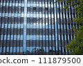 The glass wall of a modern high-rise building in the evening, reflecting blue twilight sky. 111879500