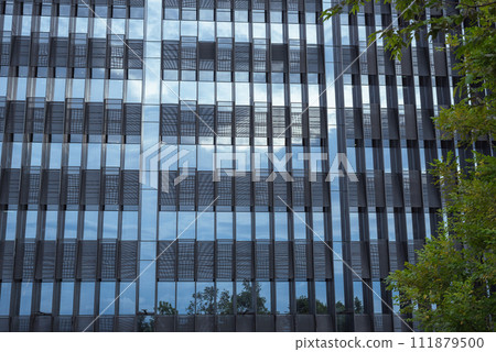 The glass wall of a modern high-rise building in the evening, reflecting blue twilight sky. 111879500