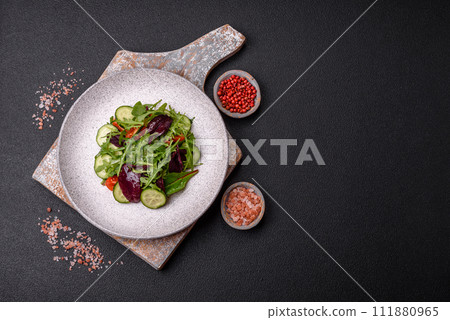 Delicious fresh salad with arugula, spinach, cucumber and cherry tomatoes in a ceramic plate 111880965