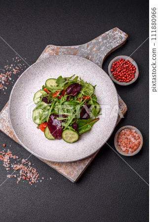 Delicious fresh salad with arugula, spinach, cucumber and cherry tomatoes in a ceramic plate 111880966