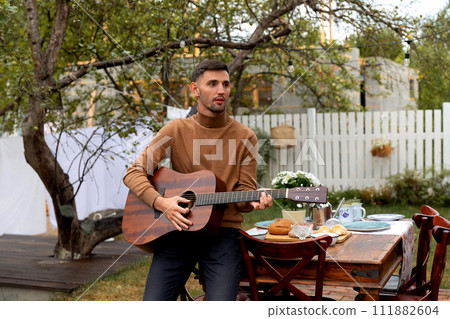 young man sits at the table and plays the guitar 111882604
