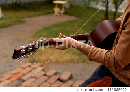 young man sits at the table and plays the guitar 111882612