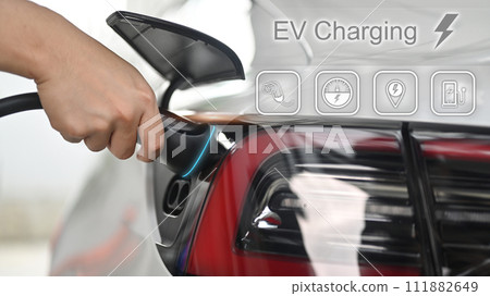 Unrecognizable man plugging electric car from charging station. Alternative clean energy concept Unrecognizable man plugging electric car from charging station. Alternative clean energy concept 111882649