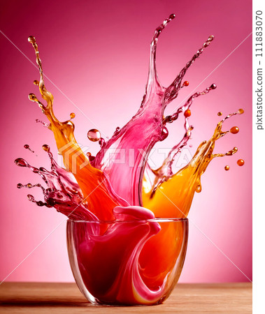 Colorful splashes of colored liquid in a glass on a pink background Colorful splashes of colored liquid in a glass on a pink background 111883070