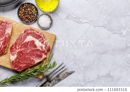 Raw ribeye steaks with savory spices 111883318