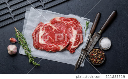 Raw ribeye steaks with savory spices 111883319
