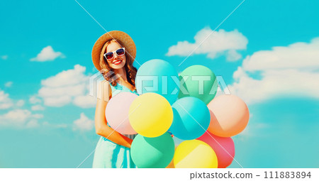 Happy smiling young woman with bunch of colorful balloons on the field on a blue sky background Happy smiling young woman with bunch of colorful balloons on the field on a blue sky background 111883894