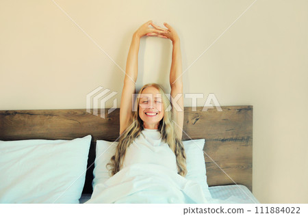 Healthy sleep, relaxed middle aged woman wakes up lying on the bed in bedroom at home Healthy sleep, relaxed middle aged woman wakes up lying on the bed in bedroom at home 111884022