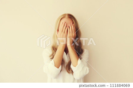 Upset sad crying young woman covering her eyes with her hands while experiencing mental Upset sad crying young woman covering her eyes with her hands while experiencing mental 111884069