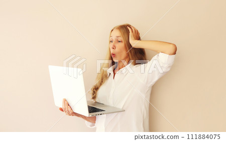 Surprised middle-aged woman looking at laptop at home 111884075