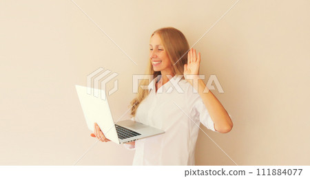 Happy caucasian middle-aged woman greets communicates with friends via video call on laptop 111884077