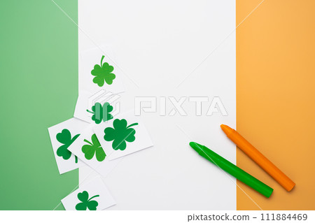 Irish flag made from color paper with cut out shamrock clover and crayons. DIY creative art craft activity for kids on St Patricks hobby 111884469
