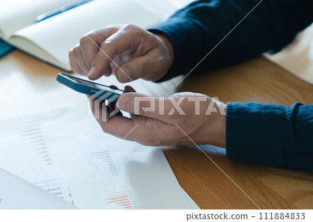 Hands of a man operating a computer and smartphone 111884833