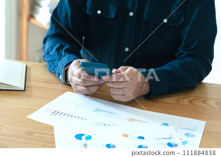 Hands of a man operating a computer and smartphone 111884838