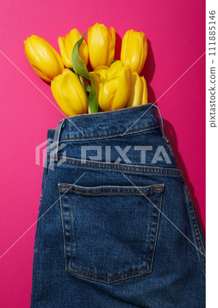 Yellow flowers in jeans on pink background, top view Yellow flowers in jeans on pink background, top view 111885146