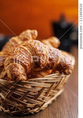 Baked tasty croissants in basket on wooden table. Baked tasty croissants in basket on wooden table. 111885610