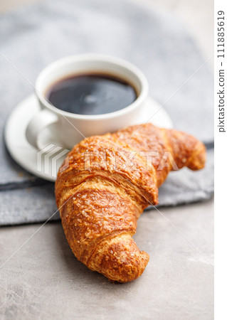 Baked tasty croissant and coffee cup on kitchen table. Baked tasty croissant and coffee cup on kitchen table. 111885619