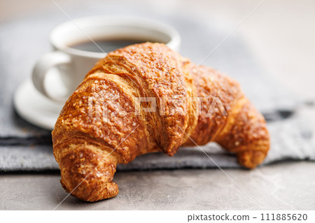 Baked tasty croissant and coffee cup on kitchen table. 111885620