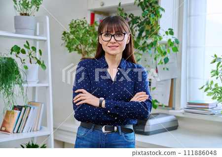 Portrait of confident smiling middle-aged woman with crossed arms at home 111886048