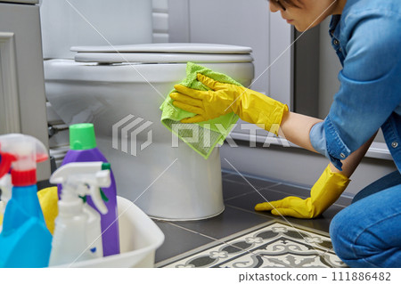 Woman in gloves using cleaning detergent clean toilet in bathroom Woman in gloves using cleaning detergent clean toilet in bathroom 111886482