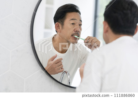 A man in his 50s brushing his teeth 111886860