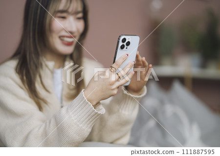 Hands of a young woman operating a smartphone 111887595