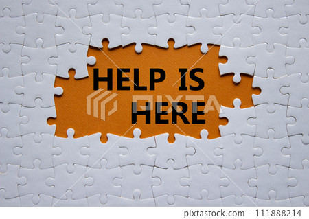Help is here symbol. Concept words Help is here on white puzzle. Beautiful orange background. Business and Help is here concept. Copy space. 111888214