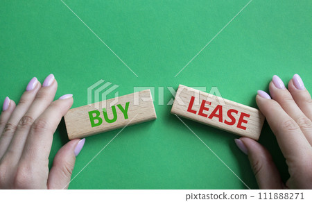 Buy or Lease symbol. Concept word Buy or Lease on wooden blocks. Businessman hand. Beautiful green background. Business and Buy or Lease concept. Copy space 111888271