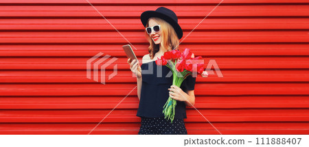 Beautiful smiling woman with smartphone holding bouquet of red rose flowers 111888407