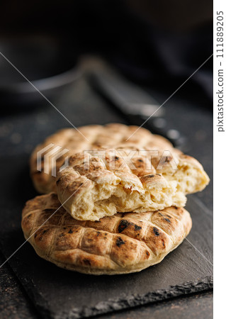 Arabic flat pita bread on cutting board on black table. 111889205