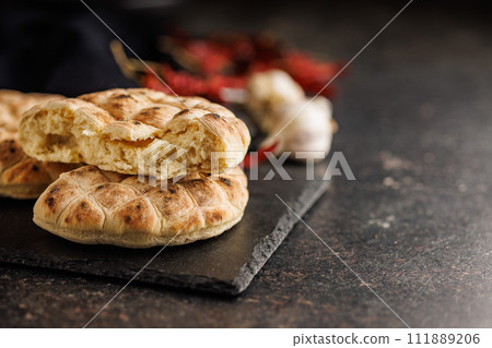 Arabic flat pita bread on cutting board on black table. 111889206