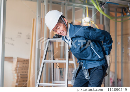 A carpenter hurts his back at the job site. A carpenter hurts his back at the job site. 111890249