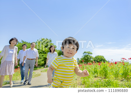 A three-generation family walking through a poppy-filled park A three-generation family walking through a poppy-filled park 111890880