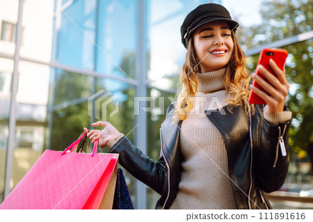 Stylish woman with shopping bags walks through the city streets. Spring Style. Stylish woman with shopping bags walks through the city streets. Spring Style. 111891616