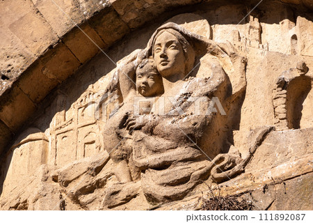 An old baroque engraved sculpture of Mary and Jesus over an entrance to the Cappella della Croce di Giorno in Volterra 111892087