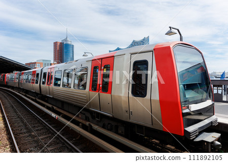 Hamburg Red Unmanned U-bahn Subway train on Baumwall station on Elevated Track with Hamburger Port Harbor Elbphilharmonie building background blue sky. Hanseatic city commute transport scenic view 111892105