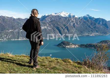 A hiker enjoying the magnificent view of Bellagio at lake Como seen from Monte Crocione 111892263