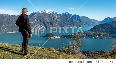 A hiker enjoying the magnificent view of Bellagio at lake Como seen from Monte Crocione A hiker enjoying the magnificent view of Bellagio at lake Como seen from Monte Crocione 111892264