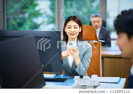 A young business woman looking at a smartphone in the office A young business woman looking at a smartphone in the office 111893112