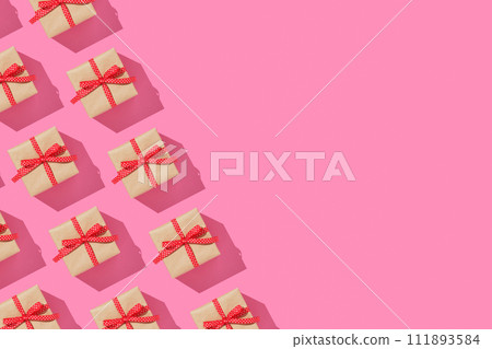 Banner with pattern of brown gift boxes on with red bows on pink background. Copyspace. 111893584