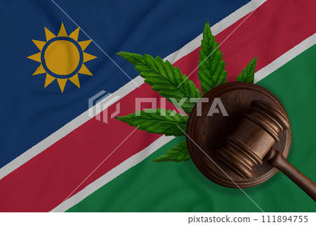 Judicial wooden gavel, fresh hemp leaf and flag of Namibia. Illegal sale and distribution of marijuana 111894755