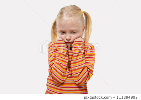 Cute little girl with blond hair wearing striped t-shirt and feeling sad 111894992