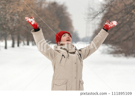 Happy young woman throwing snowflakes in the air in winter park. Laughing woman Happy young woman throwing snowflakes in the air in winter park. Laughing woman 111895109
