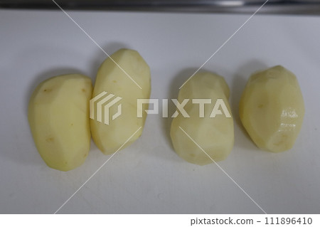 Peeled potatoes lined up on a cutting board Peeled potatoes lined up on a cutting board 111896410