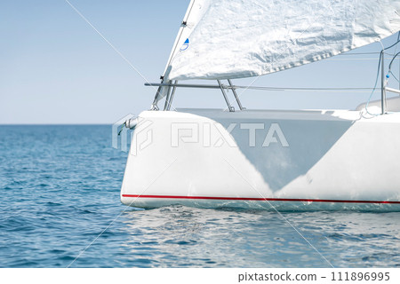 Stern with a sail of a white sport keelboat yacht 111896995