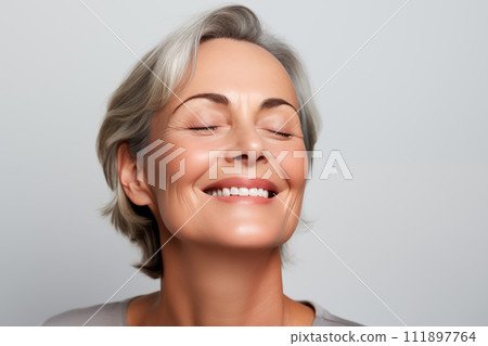 Gorgeous senior older smiling Caucasian woman with natural makeup on grey background with copy space 111897764