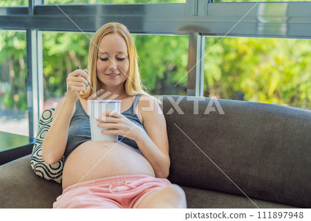 Happy pregnant young woman eating ice cream Happy pregnant young woman eating ice cream 111897948