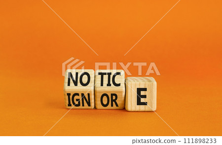 Notice or ignore symbol. Concept word Notice or Ignore on wooden cubes. Beautiful orange table orange background. Business lifestyle and notice or ignore concept. Copy space. 111898233